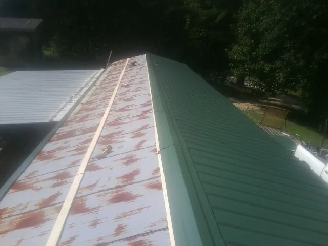 Old rusted panels beside newly installed green metal roofing — Wind Damage Roof Repair by Roofing Brothers in Beatrice