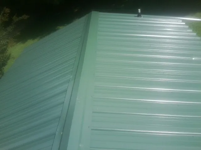 New green metal panels meeting at the ridge of a roof — Flat Roof Repair work by our crew in Beatrice