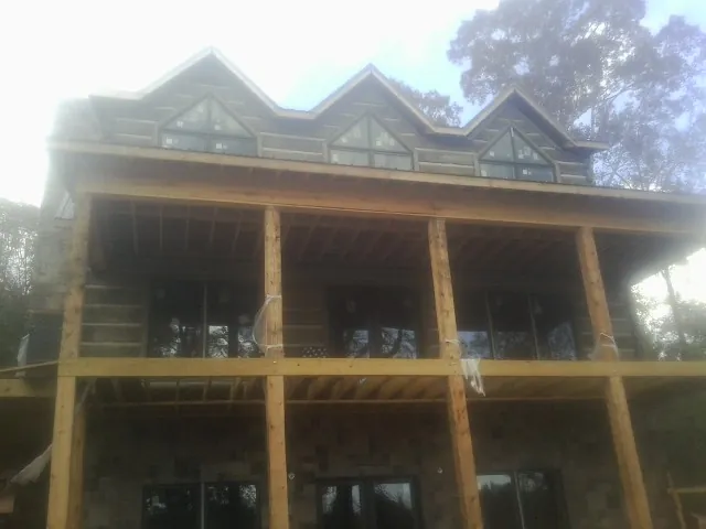 Dormers and porch framing on a large log home under construction — Roof Coating work by our crew in Beatrice