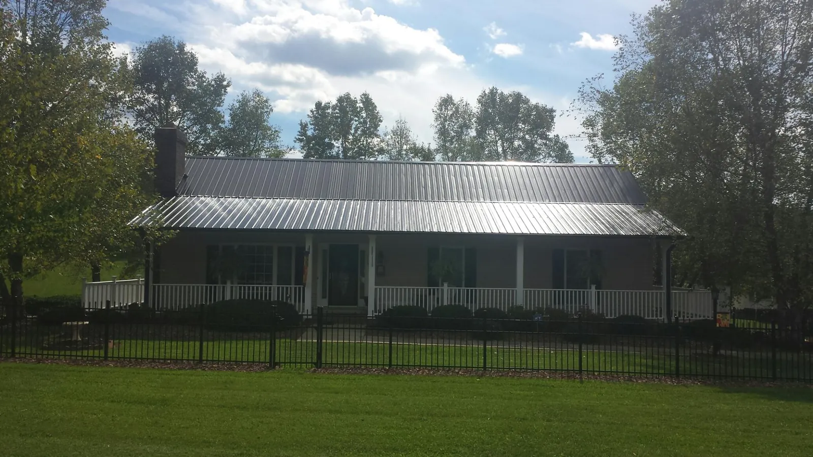 Gray metal roof on a brick ranch with a full width front porch — Gutter Guard Installation work by our crew in Beatrice