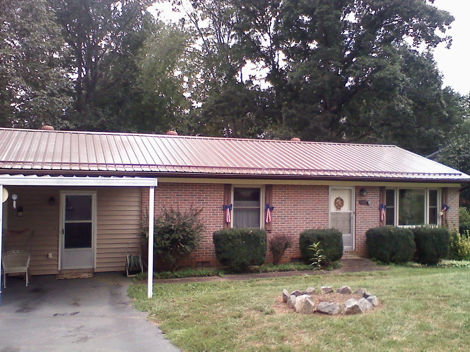 Bronze metal roof and carport on a brick ranch home — Roof Repair work by our crew in Beatrice