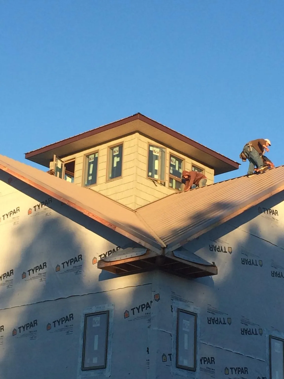Roofers working around a rooftop cupola on a new metal roof at sunset — Roof Waterproofing in Beatrice by Roofing Brothers